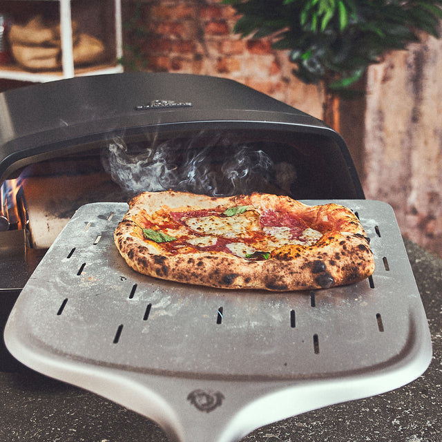Kant-en-klare pizza wordt uit de oven gehaald met een pizzaschep